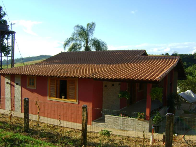 CASA EM MINAS GERAIS. Localizada em uma fazenda, esta casa de campo, projetada pela arquiteta Cláudia Breias, possui 226,67 m². A fachada traz painéis em mosaico (Slate Chiara Bianco 60x60, Portobello), esquadrias de madeira e telhas cerâmicas.