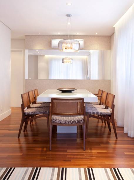 Cadeiras de madeira natural com encosto em palha trançada e assento em tecido geométrico preto e branco completam a mesa de laca. Projeto de Martinhão Neves Arquitetos.
