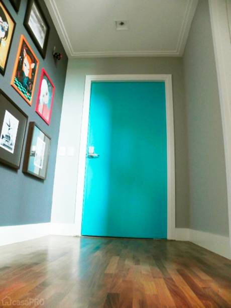 Neste hall de entrada, a porta pivotante recebeu tinta azul tifany e a arte urbana, fotografias e lembranças de viagem dão as boas vindas. Projeto de Lila Lago.