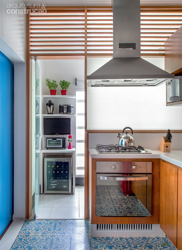 Uma divisória de madeira e vidro separa cozinha e área de serviço. O trecho ripado, no alto, garante ventilação. Projeto Renata Bartolomeu.
