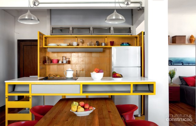 Na cozinha, o amarelo se destaca no balcão e no ladrilho hidráulico da ornatos que reveste parede e piso. Projeto Goma Oficina.