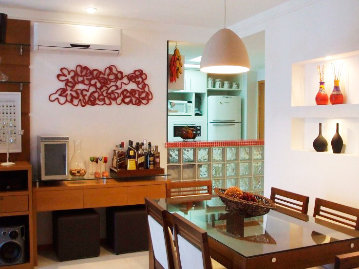 Uma parede de tijolos de vidro e pastilhas dividem esta sala de jantar da cozinha. Projeto de Ana Lucia Nunes Gomes.