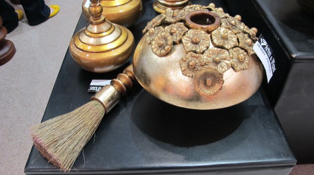 Pote branco dourado, da Artes e Ofícios, de cerâmica, folheado a ouro e com base de madeira. Sai por R$ 685.