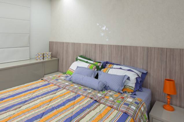A suíte das moradoras tem cabeceira da cama em madeira, além de toques coloridos no jogo de cama para trazer alegria e vida ao espaço. Projeto de Karla Amaral Madrilis. A suíte das moradoras tem cabeceira da cama em madeira, além de toques coloridos no jogo de cama para trazer alegria e vida ao espaço. Projeto de Karla Amaral Madrilis.