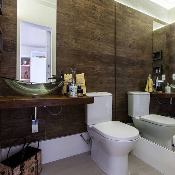 Um porcelanato que imita madeira nas paredes garante sofisticação a este lavabo de proporções diminutas (1,56 m²). Uma parede, revestida inteiramente com espelhos, aumentou a sensação de amplitude. O lavabo, assinado pela arquiteta Marcia Sayuri, faz parte de um sobrado em São Paulo (SP).