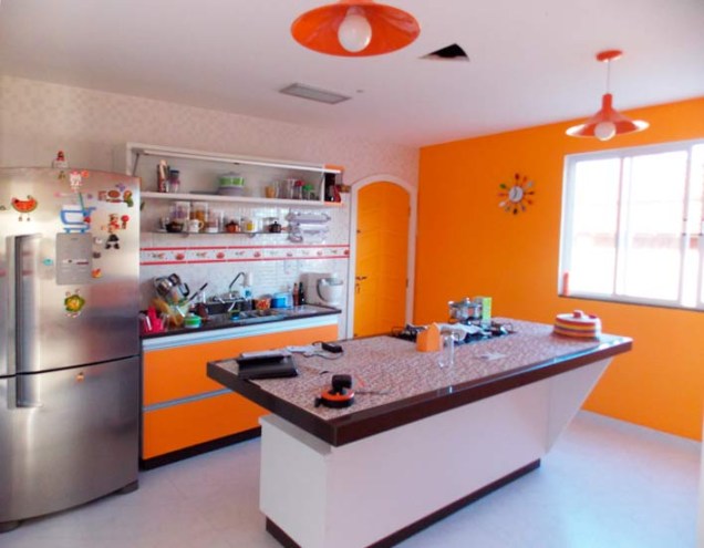 Ao mudar para uma casa, Carminha de Queiroz, que sempre viveu em apartamento, fez questão de uma cozinha ampla, com uma ilha no meio do ambiente para o cooktop. O ambiente, de 16 m², traz cores fortes nas paredes e nos armários.