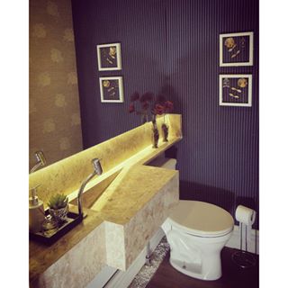 Chama atenção neste lavabo de 1,70 m² as paredes revestidas em tecido listrado na vertical. “Os seixos brancos embaixo da bancada evitaram os recortes do piso, além de contribuírem com charme junto ao tom amadeirado do revestimento”, explica os profissionais do escritório Ideação Arquitetura e Construções.