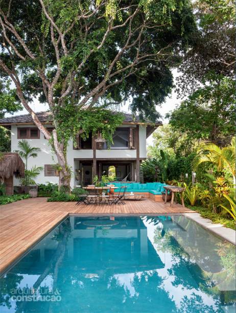 Ao redor da árvore nativa, um oiti, o deck de cumaru, com réguas de 10 cm de largura (material fornecido pela trancoso madeiras), cerca a piscina, executada com o revestimento monolítico antiderrapante Crystal Pool, da mercatto Cerâmico. Projeto do escritório Vida de Vila.