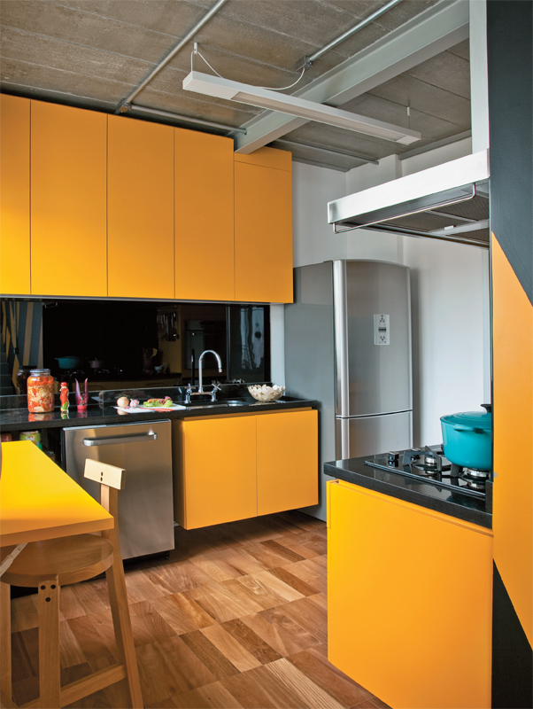 Desenhados pela arquiteta Suzana Barboza, a mesa dobrável e os armários da cozinha são de MDF revestido de laminado plástico amarelo. Na parede atrás da bancada de granito, o painel de vidro serigrafado preto (Divinal Vidros) arremata o conjunto.