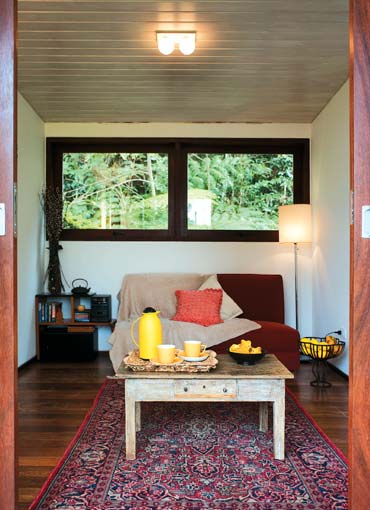 Na saleta, a janela enquadra a vista da mata, na qual o chal&eacute; est&aacute; quase en...