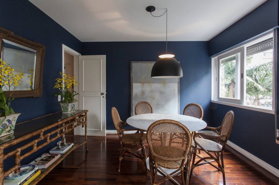 Nesta sala de jantar de 15 m², as paredes foram pintadas de azul marinho. “A mesa é de mármore carrara para contrastar com a cor das paredes e trazer luz ao ambiente”, explicam as arquitetas Adriana Pereira e Carolina Reade, que assinam o projeto. O espaço faz parte de um apartamento em São Paulo (SP).
