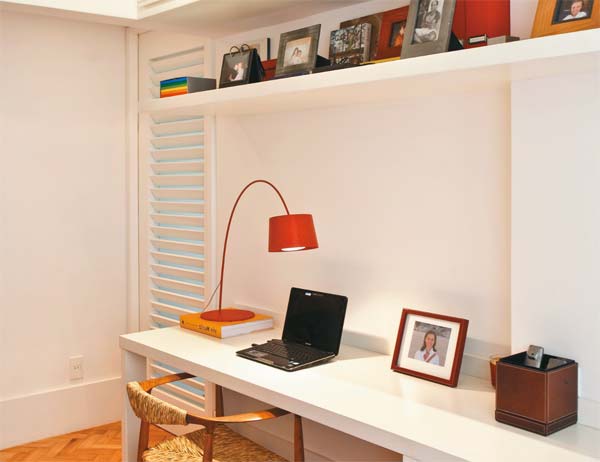 Escritório com bancada, estante e armário.