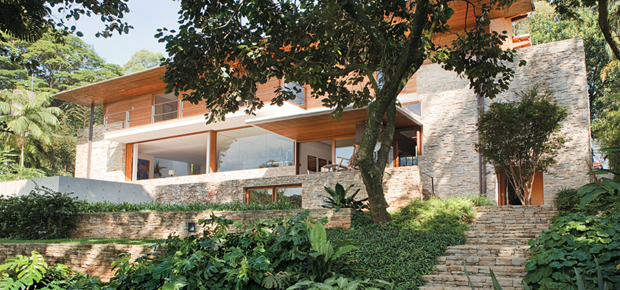 Casa de pedra, madeira e vidro se integra ao jardim em São Paulo