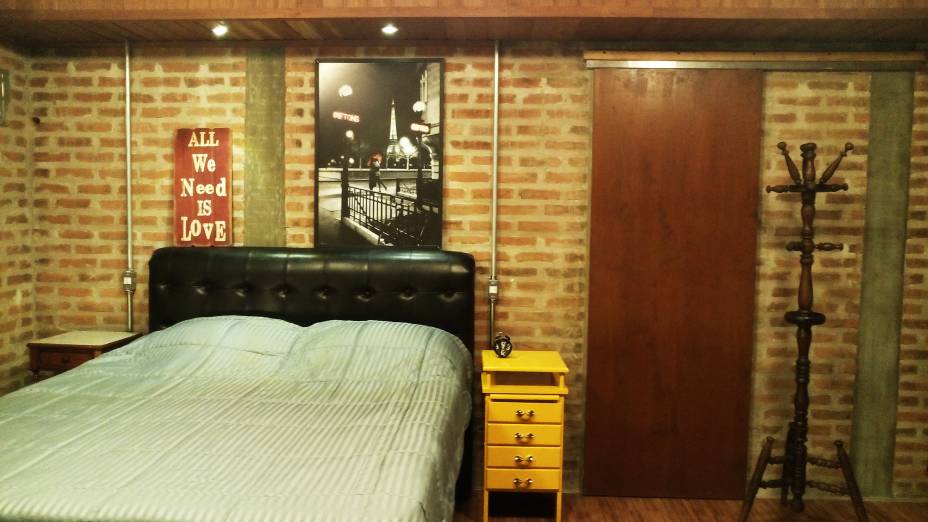 Com 3 x 5,7 m, o espaço segue a lógica dos demais ambientes da casa, com tijolos maciços formando a própria parede de fechamento, sem reboque. O piso laminado Eucafloor, em tom amadeirado, e a cabeceira da cama, em couríssimo preto, dialogam com a parede de tijolos. O colorido ficou por conta do criado mudo amarelo. O projeto é da arquiteta Bianca Ferreira.