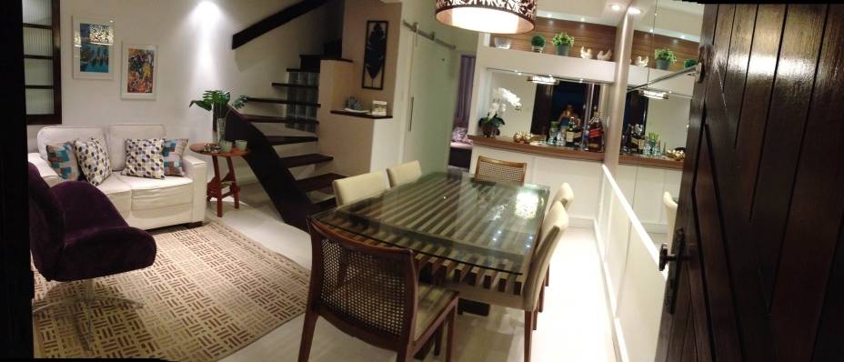 Na sala de jantar integrada ao estar desta casa em Salvador (BA), o piso é um porcelanato bege para dar amplitude ao espaço. O papel de parede, que imita textura de couro, foi escolhido no tom marrom. “Foram mescladas outras cores com a produção dos adornos e das almofadas. A poltrona tem um tom de roxo pontual para quebrar a rigidez da paleta de cores”, explica a arquiteta Carolina Santana.