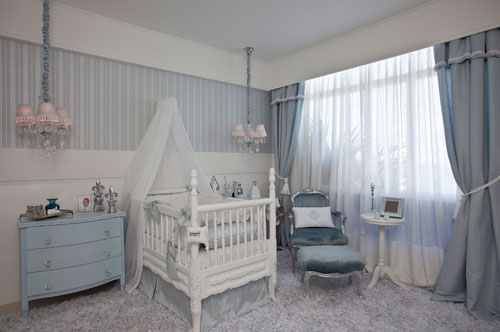 Uma suíte masculina para um bebê com predomínio de azul e branco. Este foi o projeto da arquiteta Edelzuita Alcântara para a Casa Cor Bahia. O enxoval que envolve o berço é feito de seda e linho. O painel listrado ao fundo é um papel de parede. A poltrona Luis XV com acabamento em prata e estofado azul é dos destaques do ambiente.