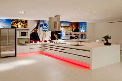 CASACOR Brasília - O Espaço do Chef, criado pela designer de interiores Beth Rosso, possui linhas retas e predomínio de branco, principalmente na bancada feita de corian. A iluminação de leds permite a mudança de cor abaixo da bancada. Ao fundo, um painel de fotografias da cidade de Brasília remete ao homenageado nacional da mostra, o arquiteto e urbanista Lúcio Costa. As fotos são de autoria de Rafael Zarth.