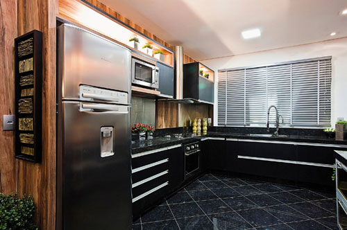 CASACOR Mato Grosso - Pensada para pessoas vaidosas, a Cozinha assinada pela designer de interiores Claudia de Oliveira utiliza vários espelhos em sua composição. Amplas bancadas percorrem as paredes e dão praticidade ao projeto. Destaque para a cuba preta de sobrepor de vidro e para as persianas que simulam inox. No piso, granito nacional do tipo Amazon Forest. O uso de madeira de demolição faz o contraponto e acrescenta um toque rústico.