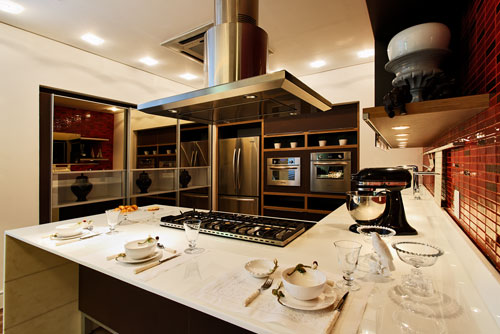 CASACOR Santa Catarina - Cozinha Mulher. Uma cozinha bonita, chique e tecnológica. Foi a partir desta proposta que os arquitetos Carlos Lupatini, Michel Lima, Ana Cláudia Ramos, Bianca Lombardi e Gabriela Saraiva Accorsi criaram a cozinha do Apartamento da Mulher na Casa Cor Santa Catarina 2010. As gavetas do armário têm uma abertura elétrica de sistema cool drive – que abre apenas com o toque. A bancada foi feita em Nanoglass – composto sintético brilhante com a resistência do granito. Os arquitetos optaram por um cooktop e por uma coifa luxuosa.