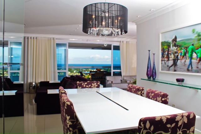 Na sala de jantar de 20 m² deste apartamento em Salvador (BA), bege, prata e beringela formam a paleta de cores. A mesa em resina off white e cadeiras estofadas em tecido compõem o espaço. “O objetivo do espaço é ser utilizado para as refeições. Porém, por ser pequeno em relação à área total do apartamento, instalamos espelhos em uma das paredes para ampliá-lo”, explica a arquiteta Celeste Leão.