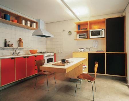 18 m&sup2;: Misturar vermelho e preto &eacute; poss&iacute;vel. Mas, para tornar o conjunto harm&ocirc;nico, tomaram-se alguns cuidados neste projeto: a tonalidade uniforme dos ladrilhos hidr&aacute;ulicos do piso, a leveza do arm&aacute;rio e da bancada central suspensos e o tom natural das pranchas de madeira equilibram a combina&ccedil;&atilde;o. O desenho dos m&oacute;veis tamb&eacute;m colabora: dispensa puxadores e dosa corretamente portas e nichos. Criamos uma proposta simples e despojada, utilizando materiais com essas mesmas caracter&iacute;sticas. O charme fica por conta das cores, diz o arquiteto Luiz Junqueira, que atuou com o s&oacute;cio, Fernando V&aacute;zquez.