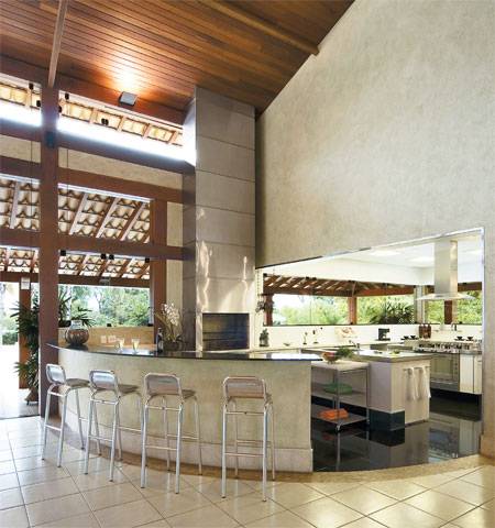 65 m&sup2;: Cora&ccedil;&atilde;o da &aacute;rea de lazer, que tem piscina, spa, sauna, sal&atilde;o para 50 pessoas e home theater, esta cozinha gourmet prima pela eleg&acirc;ncia. Encarregada do projeto, a arquiteta Cristina Menezes, de Belo Horizonte, escolheu acabamentos de primeira, como o quartzito preto absoluto de piso e balc&atilde;o e o aglomerado sint&eacute;tico da bancada. Duas ilhas centrais, uma para coc&ccedil;&atilde;o e outra para lavagem de lou&ccedil;a, facilitam o trabalho do mestre-cuca, fun&ccedil;&atilde;o tamb&eacute;m dos dois carrinhos de a&ccedil;o inox com rod&iacute;zios. Para poder variar o card&aacute;pio, o espa&ccedil;o conta ainda com uma churrasqueira pr&eacute;-moldada, vizinha do balc&atilde;o. As paredes receberam laminado branco, e as janelas s&atilde;o de vidro temperado cristal, garantia de integra&ccedil;&atilde;o com o exterior.
