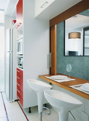 7 m&sup2;: Listras no piso, tra&ccedil;adas com pastilhas de vidro vermelhas, alongam esta cozinha e conferem &agrave; proposta o estilo descontra&iacute;do encomendado &agrave; arquiteta Adriana Fontana, de S&atilde;o Paulo. Medindo 2,15 x 3,20 m, ap&oacute;s a incorpora&ccedil;&atilde;o de um banheiro sem uso, o espa&ccedil;o recebeu uma porta de correr de vidro pontilhado na passagem para a lavanderia  solu&ccedil;&atilde;o que ajuda a driblar as dimens&otilde;es acanhadas e deixa entrar a luz natural vinda da &aacute;rea de servi&ccedil;o. O passa-pratos aberto para a sala do apartamento durante a reforma pode ser fechado, barrando odores e disfar&ccedil;ando a bagun&ccedil;a se houver lou&ccedil;a na pia.