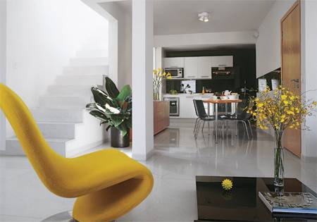 O piso de granilite e as paredes brancas, al&eacute;m de pr&aacute;ticos, refor&ccedil;am ainda mais a sensa&ccedil;&atilde;o de amplitude. No fundo, onde fica a cozinha, o toque de cor vem do vidro laminado verde que cobre a parede atr&aacute;s da pia, dos arm&aacute;rios e dos eletrodom&eacute;sticos.