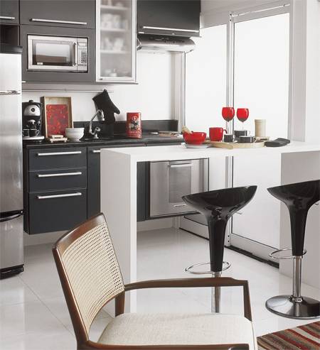 A cozinha, &eacute; sutilmente separada da sala por uma bancada de madeira laqueada de branco e acompanhada por banquetas italianas de design contempor&acirc;neo.