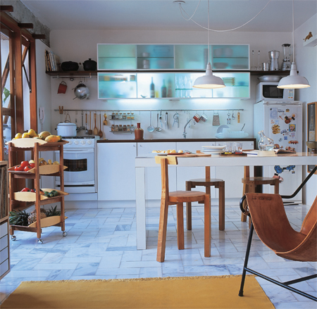 A cozinha esbanja luminosidade, trunfo da combinação do piso de mármore, dos armários brancos e das amplas janelas.