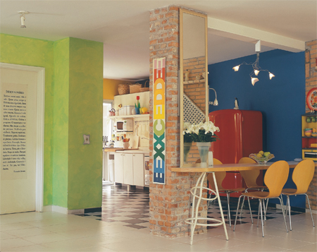 Supercolorida e totalmente aberta, a cozinha une-se à sala por meio do balcão de madeira.