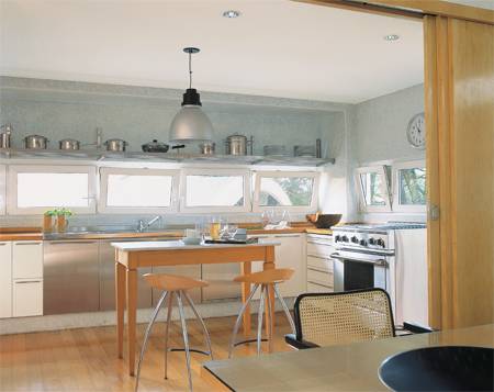 Pastilhas de vidro branco-gelo nas paredes e piso de madeira tauari, protegida com sinteco. Se a porta de marfim, com seis folhas de correr, fica aberta, a sala de jantar se transforma na extens&atilde;o da cozinha.