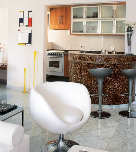A cozinha faz fronteira com a sala apenas pelo inusitado balc&atilde;o circular revestido de pastilhas de casca de coco.