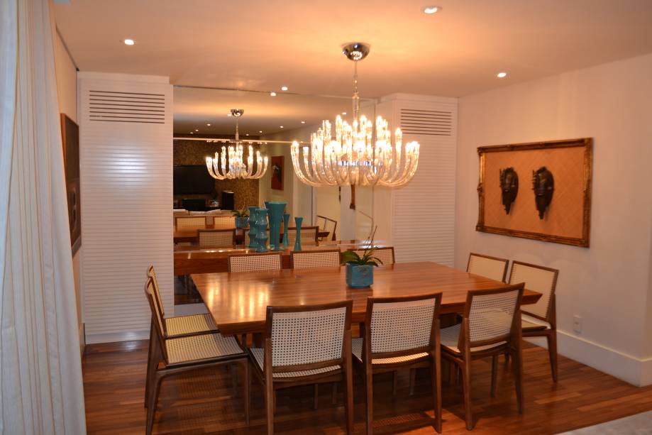 Para acomodar dez lugares à mesa, mais as caixas sorround do home theater, a solução foi projetar a mesa e o aparador, executados em madeira pau ferro. As cadeiras com palhinha são da Breton. “O espaço ainda precisava estar em harmonia com as cores e acabamentos utilizados no living”, conta a arquiteta de interiores Deisi Tokumaru.