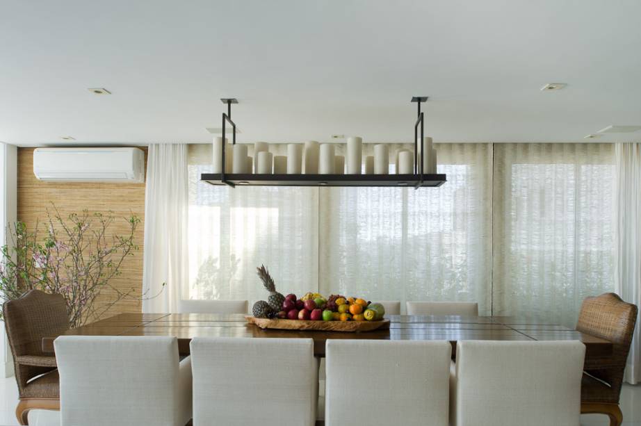 Piso marmoglass branco, cadeiras estofadas e tampo de madeira maciça compõem a sala de jantar deste apartamento em São Paulo (SP). No espaço de 40 m², há a integração de sala de jantar, home theater e cozinha. “Utilizamos materiais rústicos de forma moderna”, conta o arquiteto Erice Neto.
