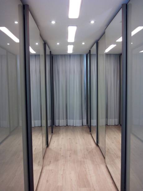A arquiteta Fernanda Alvarez teve como missão projetar um closet num espaço comprido, de área total de 18,29 m². “Por ser um espaço muito comprido, onde teríamos um grande número de portas, optamos por intercalar portas de vidro e espelho para dar mais movimento e brincar com o reflexo e o brilho vidro pintado da mesma cor do móvel”, conta a profissional. O closet, feito em MDF branco e fendi da Guararapes, é de um casal em Curitiba (PR).