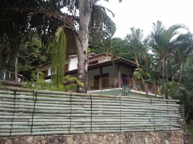 Construída na cidade São Sebastião (SP), esta casa foi projeta para ter ares de de fazenda – com a peculiaridade de ter uma vista privilegiada para a Serra do Mar. Projetada pelo arquiteto Fabio Melo, o muro frontal tem como base pedras de seixo amarelo e sua parte superior é de eucalipto autotravado sobreposto e preso com anéis metálicos para estabilizar.