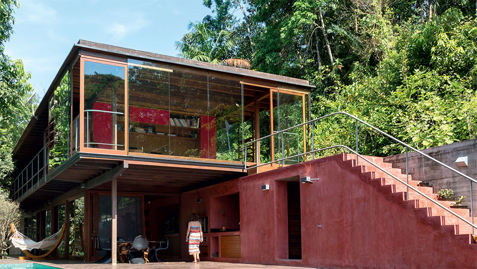 Casa de madeira e vidro se confunde com a mata ao redor