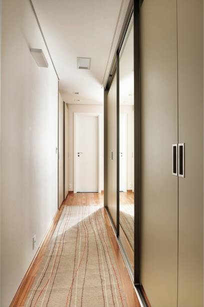 No corredor de 15 m² de área total, o closet de madeira ganhou pintura automotiva. “Ele promove a passagem entre a entrada do suíte máster e também esconder outro closet, atrás da porta central”, contam as arquitetas do escritório Madi Arquitetura e Design. O projeto foi feito em São Paulo (SP).