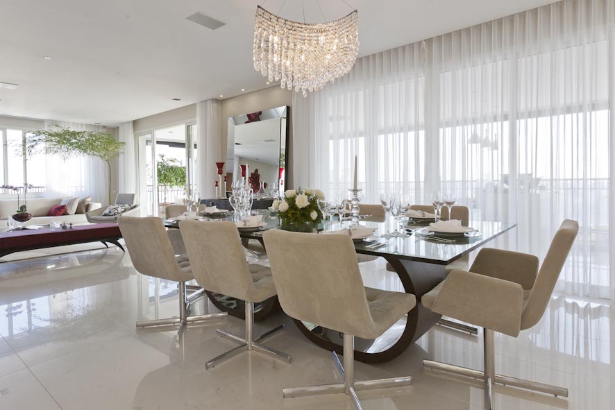 A sala de jantar deste apartamento ganhou revestimento de porcelanato Portinari, com pintura da Suvinil na cor lascas de macadâmia. A mesa foi feita pelo designer Sergio Faher. “A iluminação se dá pelo lustre em cristal da Scatto, dando  brilho e delicadeza”, conta a arquiteta e designer de interiores Mayra Lopes.