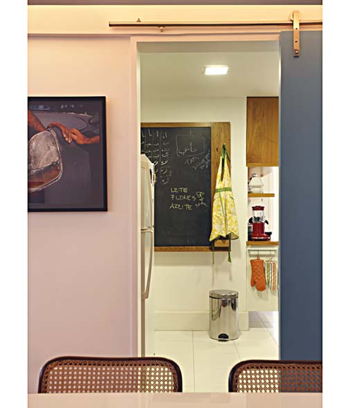 Ao se abrir a porta de correr entre a cozinha e a sala de jantar, vê-se um quadro-negro, que serve para anotar recados e lembretes. Projeto de Renata Bartolomeu.