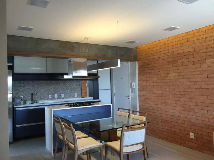 O revestimento Lepri, da linha Bricks, imita tijolos aparentes nesta sala de jantar integrada à cozinha. O espaço, de aproximadamente 18,15 m², ainda conta com mesa devidro e bancada em aglostone branco prime, um tipo de mármore artificial. Os elementos seguem a linha de materiais naturais, com destaque para o concreto na viga e o revestimento de tijolos aparentes. O projeto é da arquiteta ​Adriana Victorelli para uma casa em São Paulo (SP).
