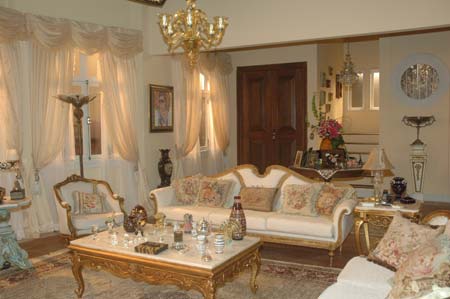 É a casa dourada da novela. Walter (Antonio Grassi), de Chamas da Vida, mora ali com sua esposa Arlete (Jussara Freire). A mulher gosta de tudo que brilha, por isso o dourado está presente em toda a decoração. Apesar de ter dinheiro, Arlete não é uma mulher fina. Gosta de decorar sua casa com adereços e bibelôs que podem ter sido adquiridos tanto no Saara (a 25 de março carioca) como num antiquário. Também adora colocar quadros com pinturas de sua própria imagem. “Para não deixar esse ambiente muito pesado, optei por usar tecidos claros e com estampas que puxam para o pastel”, afirma Ana Paula Antunes Lopes. Uma parte da mobília foi adquirida no acervo da Rede Record e o restante a cenógrafa mandou fazer. Os objetos de decoração são do Saara e de fornecedores da emissora.Credito: TV GLOBO - Munir Chatack
