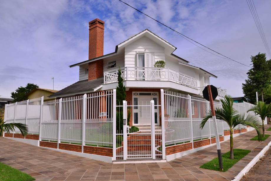 A inclinação do telhado e a rusticidade dos tijolos à vista (colocados na obra) combinadas com a delicadeza das esquadrias e detalhes dos peitoris das sacadas de madeira na cor branca, lembram o estilo colonial americano. O projeto é das arquitetas Patrícia Oliveira, Rosana Oliveira e Francieli Lamberti e do engenheiro civil João Cézar Oliveira.