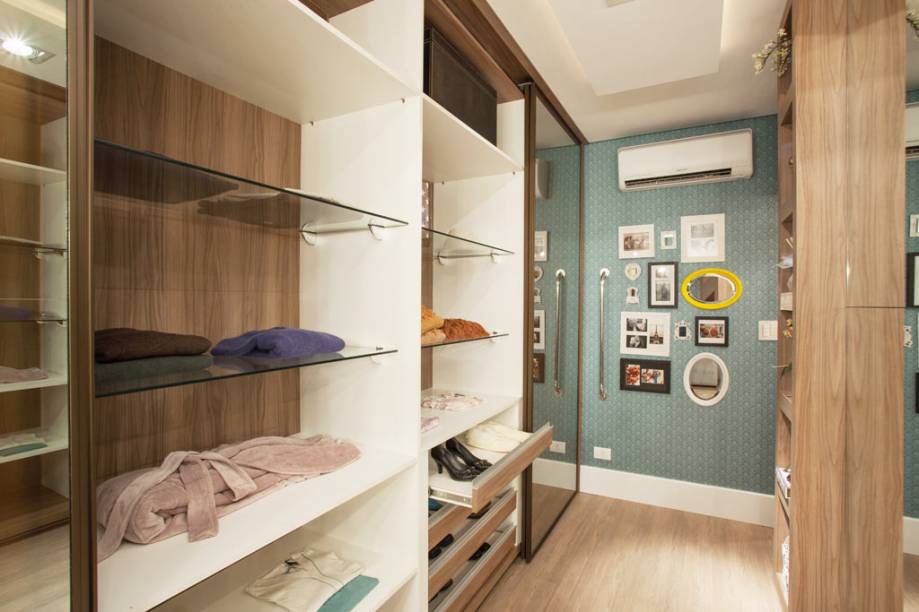 Projetado para um casal de idosos, o closet é de MDF e as portas são revestidas de vidro reflecta float bronze com película adesiva interna. Já as prateleiras internas foram feitas também em MDF e ganharam vidro temperado de 8 mm. “Escolhemos prateleiras de vidro para facilitar a visão do que foi guardado nelas, assim dispensamos o uso de bancos ou outros objetos que poderiam causar acidentes. Além disso, como se tratava de um closet voltado para os avós, ele também foi pensado na acessibilidade de cadeirantes, que estariam em uma altura inferior. A barra metálica na lateral foi colocada para facilitar o acesso as roupas, ou para que o idoso se segure caso queira levantar, ou ainda simplesmente para apoiar-se quando estiver se trocando”, contam os arquitetos Fernando Sabatini, Paula Danielly Said, Mariana Molina e Renata Venazzi, que fizeram o ambiente para a mostra CASA.COM 2013, em Maringá (PR).