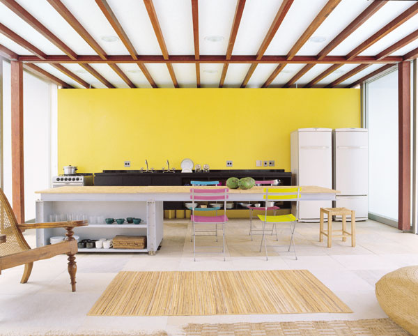 A parede amarela serve de recurso para delimitar a área da cozinha, que ocup...