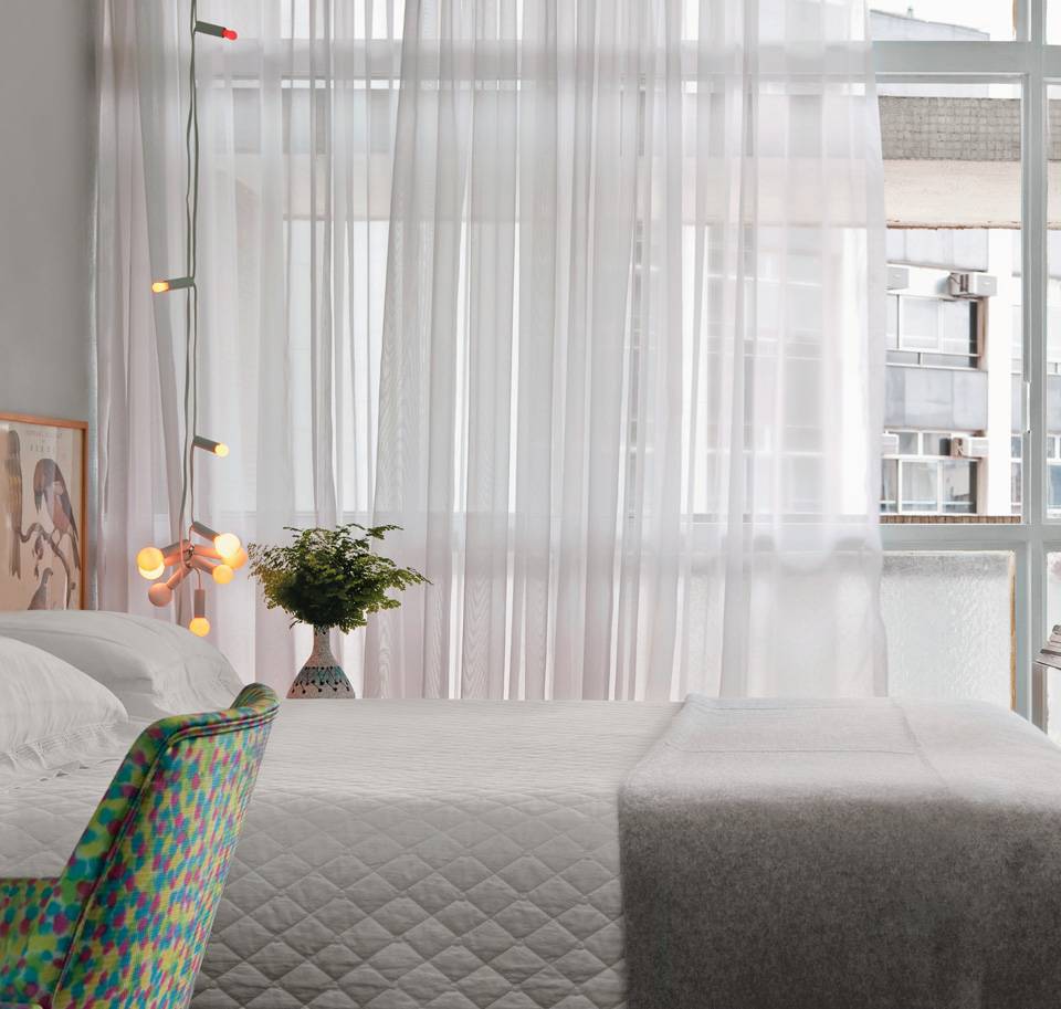 Cores suaves valorizam este apartamento no edif&iacute;cio Copan, na capital paulista. &ldquo;Usei cores frescas e priorizei m&oacute;veis delgados, que dialogam com a &eacute;poca do Copan, os anos 1950&rdquo;, detalha o propriet&aacute;rio e designer de interiores Gabriel Valdivieso. A cabeceira tem lumin&aacute;ria comprada no MoMA (Museu de Arte Moderna), em Nova York. Poltrona da Casa Velha Antiguidades com tecido da Cinerama.