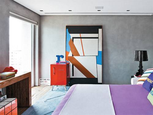 S&oacute;brios, os revestimentos desta su&iacute;te permitem brincadeiras na decora&ccedil;&atilde;o. H&aacute; um saud&aacute;vel jogo de cores sobre a base cinza, com lil&aacute;s, vermelho, preto e azul. Repare nas almofadas com nomes de rem&eacute;dios, de Sergio K., e na banqueta Cubo M&aacute;gico, do pr&oacute;prio arquiteto Guilherme Torres (DBox), que assina esse espa&ccedil;o de alma masculina. Tela abstrata de Tuneu.