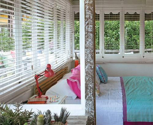 O charme deste quarto (que vira sala, quando necess&aacute;rio, devido ao espa&ccedil;o diminuto da morada) vem das cores e das estampas. Paredes, persianas e as mesinhas laterais formam a base branca para dar destaque &agrave; lumin&aacute;ria vermelha e &agrave; roupa de cama. Colcha de algod&atilde;o da &Aacute;rea Objetos e manta azul da Fina Flor.