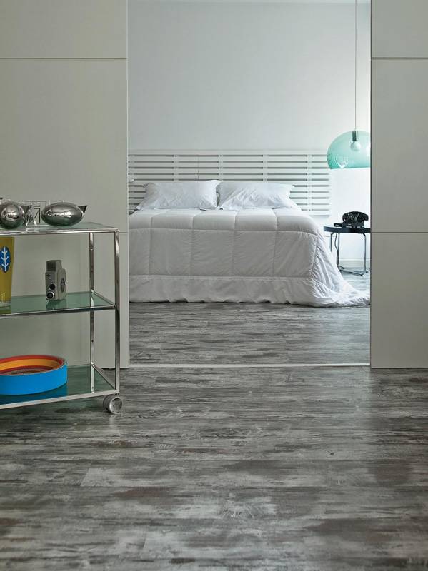 O piso laminado cinza-escuro Vintage (da alem&atilde; Kronotex, na Postigo) permitiu a este quarto de base branca aproveitar o aconchego da madeira com uma cor que foge do padr&atilde;o. A arquiteta Mara&iacute; Valente assina o espa&ccedil;o.